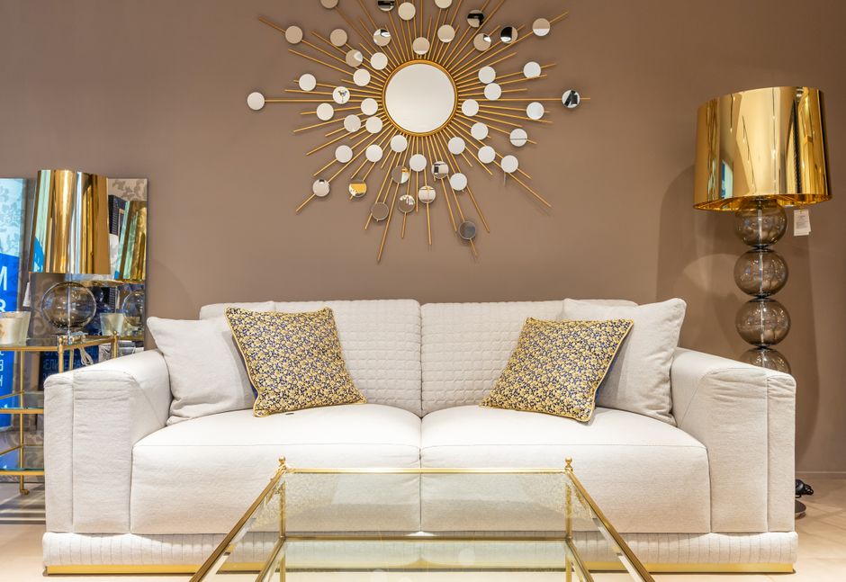 Comfortable white sofa with pillows placed near with floor lamp at wall with decorative elements in stylish living room of apartment